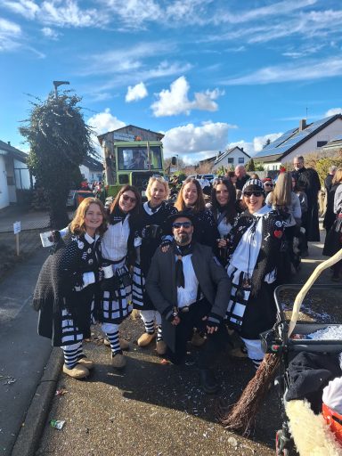 Gruppe von Personen in Karnevalskostümen, fröhlich auf der Straße versammelt.