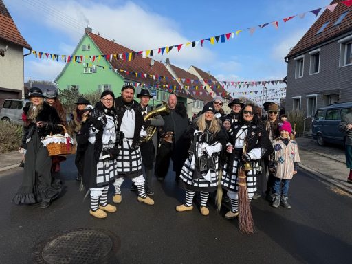 Eine Gruppe von bunt gekleideten Menschen feiert auf einer Straße mit Bißchen.