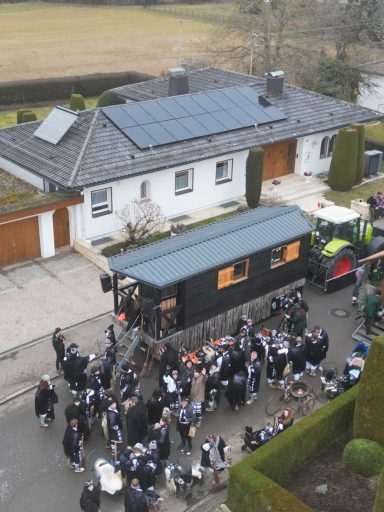 Menschenmenge versammelt sich um ein mobiles Catering vor einem modernen Haus.