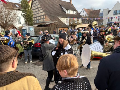 Karnevalsfeier mit Musikern, Tänzern und bunten Kostümen in einer Stadtstraße.