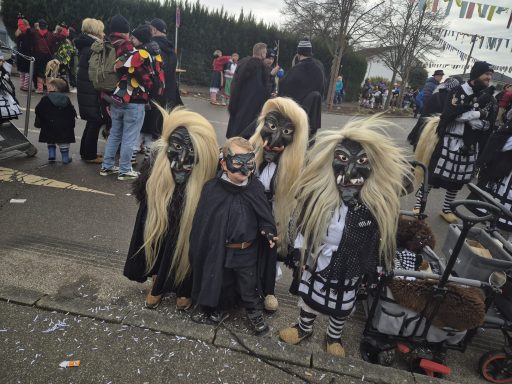 Vier Personen in Kostümen mit langen Haaren und Masken stehen auf einer Veranstaltung.
