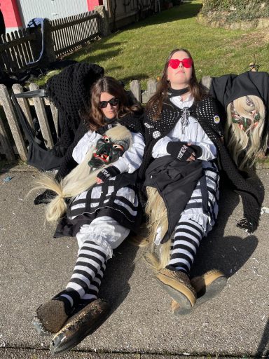 Zwei Personen in schwarzen und weißen Outfits entspannen auf dem Boden.