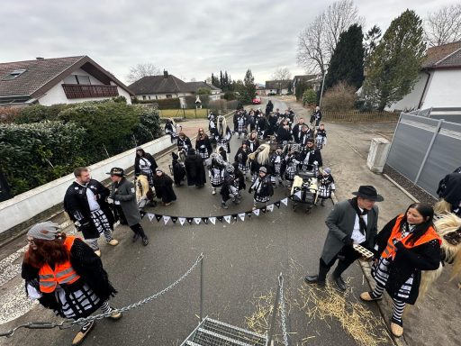Gruppierung von Menschen in schwarzer und oranger Kleidung, die durch eine Straße ziehen.