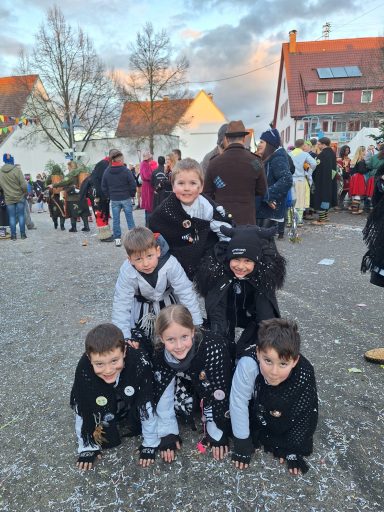 Sechs Kinder in sportlicher Kleidung bilden einen menschlichen Turm bei einem Fest.