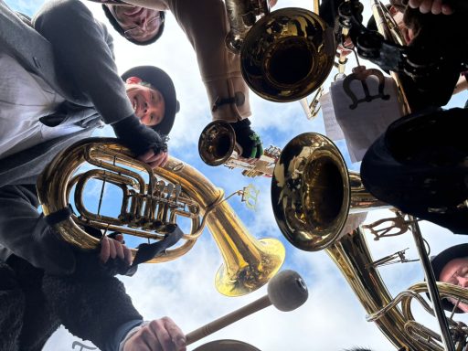 Musiker halten Blasinstrumente wie Trompeten und Tubas in die Höhe.