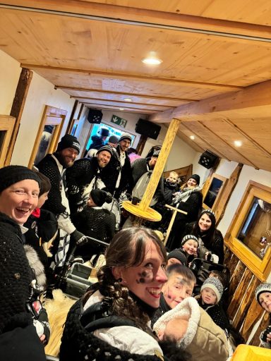 Eine Gruppe von fröhlichen Menschen in einem festlichen Raum, alle in schwarzen Outfits.