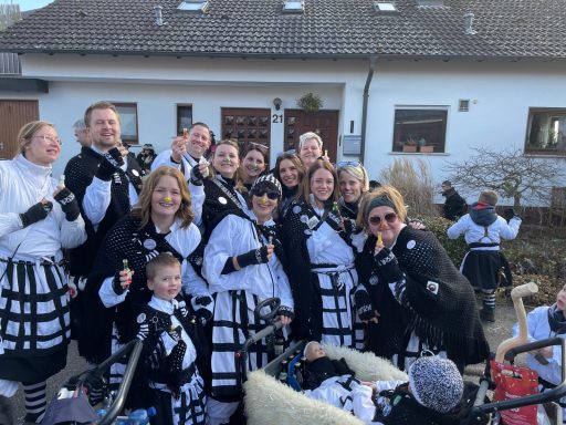 Gruppe von Feiernden in historischen Kostümen mit schwarz-weißen Outfits.