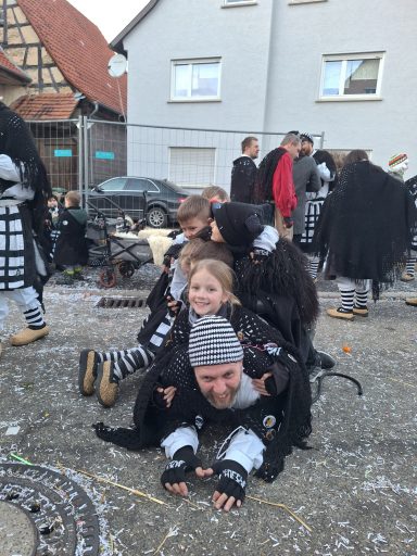 Gruppenkostümierte Kinder und Erwachsene stehen und knien in einer festlichen Umgebung.