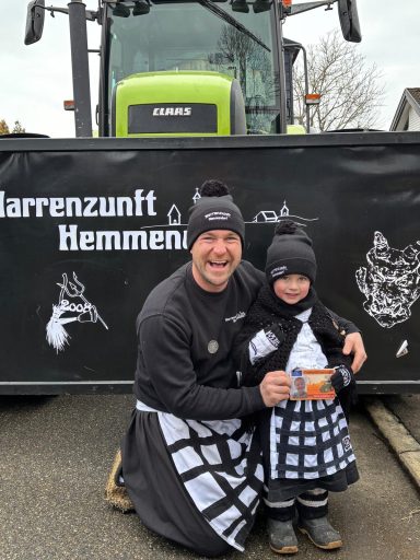 Ein Mann und ein Kind in Trachtenkleidung stehen vor einem Traktor.