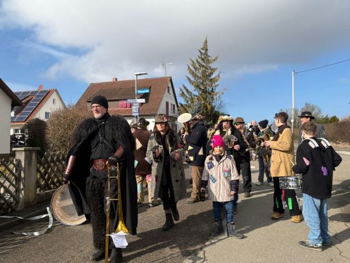 Menschenmenge mit Musikinstrumenten, die ausgelassen auf einer Straße feiert.