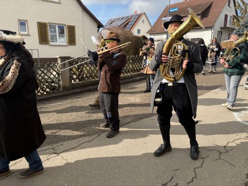 Musikanten in Tracht spielen Blasinstrumente beim Umzug auf einer Straße.